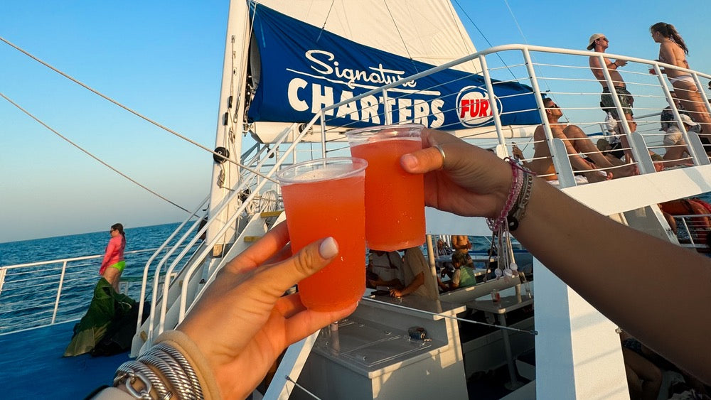 Snorkel and sunset sail combo tour in Key West with guests snorkeling and enjoying rum drinks during a sunset cruise